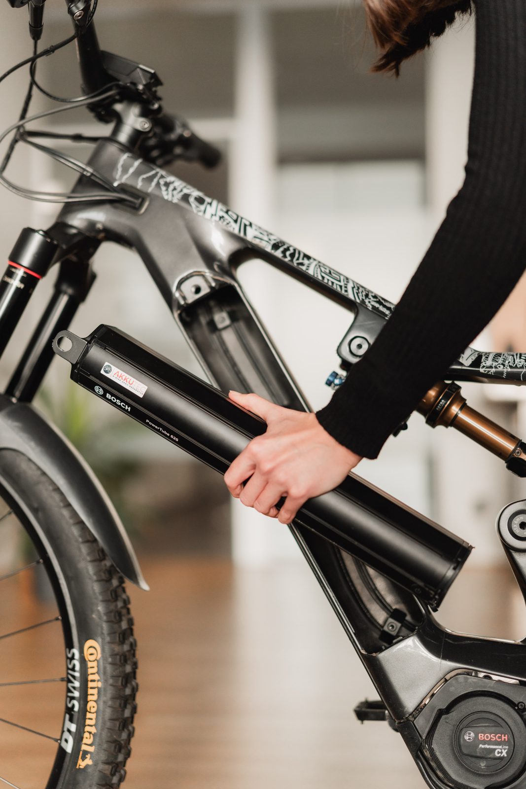 Person setzt einen E-Bike-Akku in ein E-Bike ein